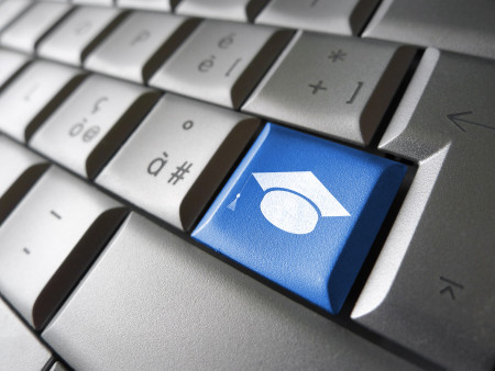 Online education and e-learning concept with graduation hat icon and symbol on a blue computer key for school and online educational business.